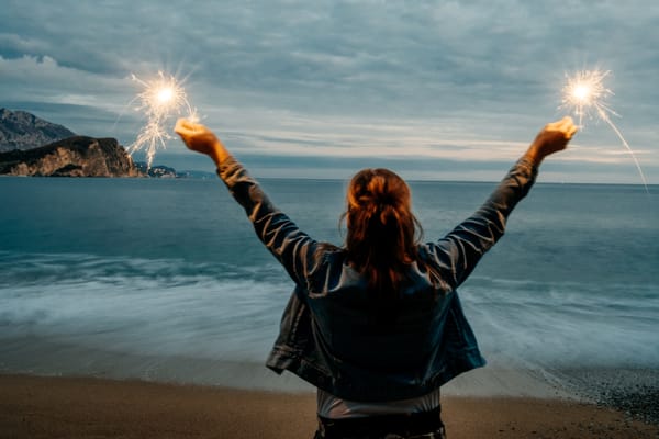A woman holding two glowing sparkles, symbolizing focused energy and the power of attraction.